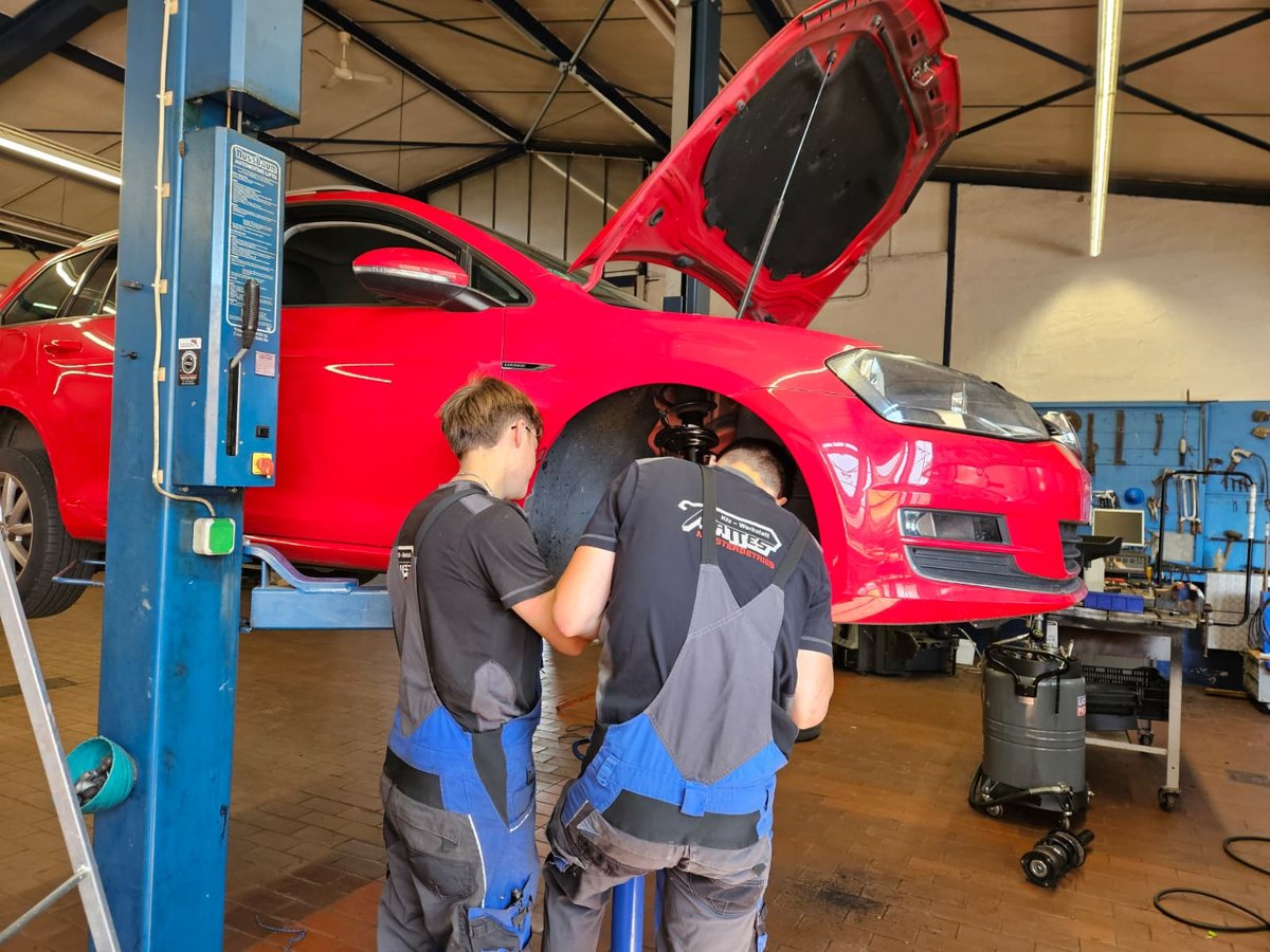 Zwei Mechaniker der Werkstatt Mattes bei der Arbeit an einem Fahrzeug auf der Hebebühne